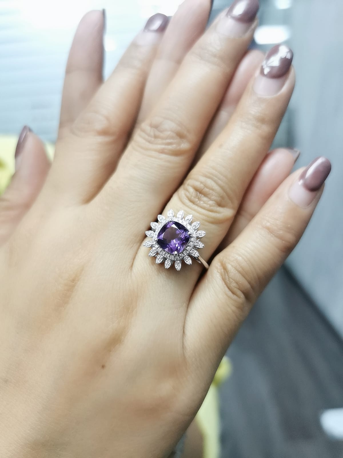 Elegant amethyst and diamond sunburst ring in 18K gold, featuring a 1.30-carat cushion-cut amethyst and 0.17-carat diamonds in a radiant halo design.