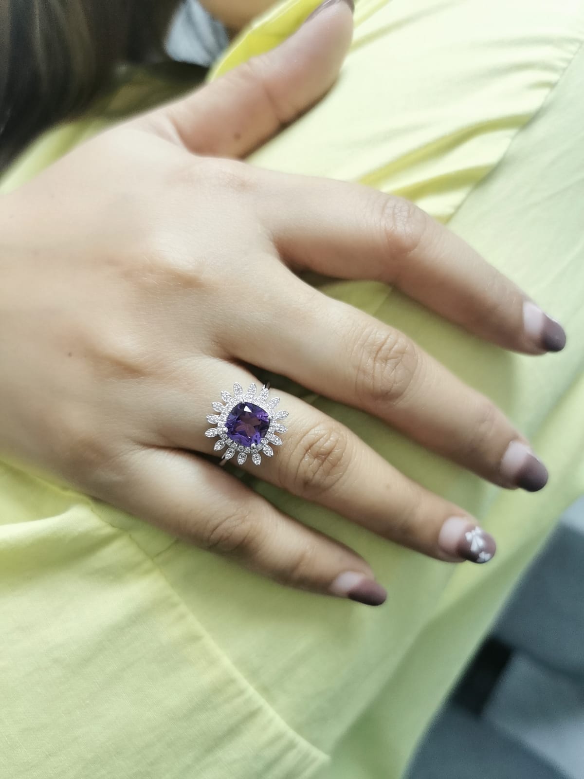 Elegant amethyst and diamond sunburst ring in 18K gold, featuring a 1.30-carat cushion-cut amethyst and 0.17-carat diamonds in a radiant halo design.