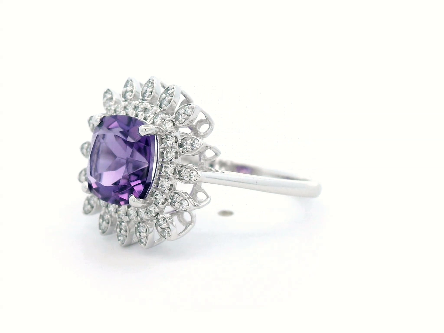 Elegant amethyst and diamond sunburst ring in 18K gold, featuring a 1.30-carat cushion-cut amethyst and 0.17-carat diamonds in a radiant halo design.