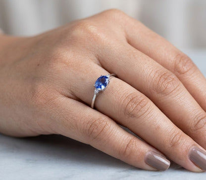 18K white gold oval tanzanite and diamond ring with two round diamond side accents.