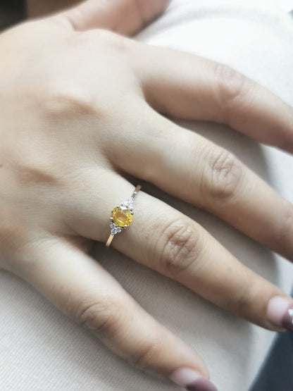 18K yellow gold ring with a 0.80-carat oval yellow sapphire and 0.09-carat diamond accents in a three-stone setting, elegant and timeless design.