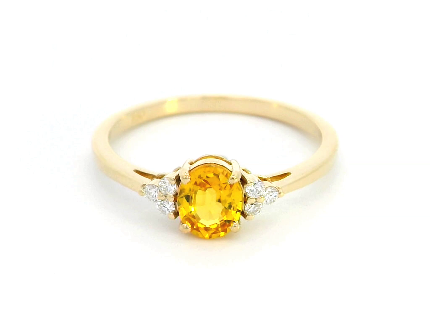 18K yellow gold ring with a 0.80-carat oval yellow sapphire and 0.09-carat diamond accents in a three-stone setting, elegant and timeless design.