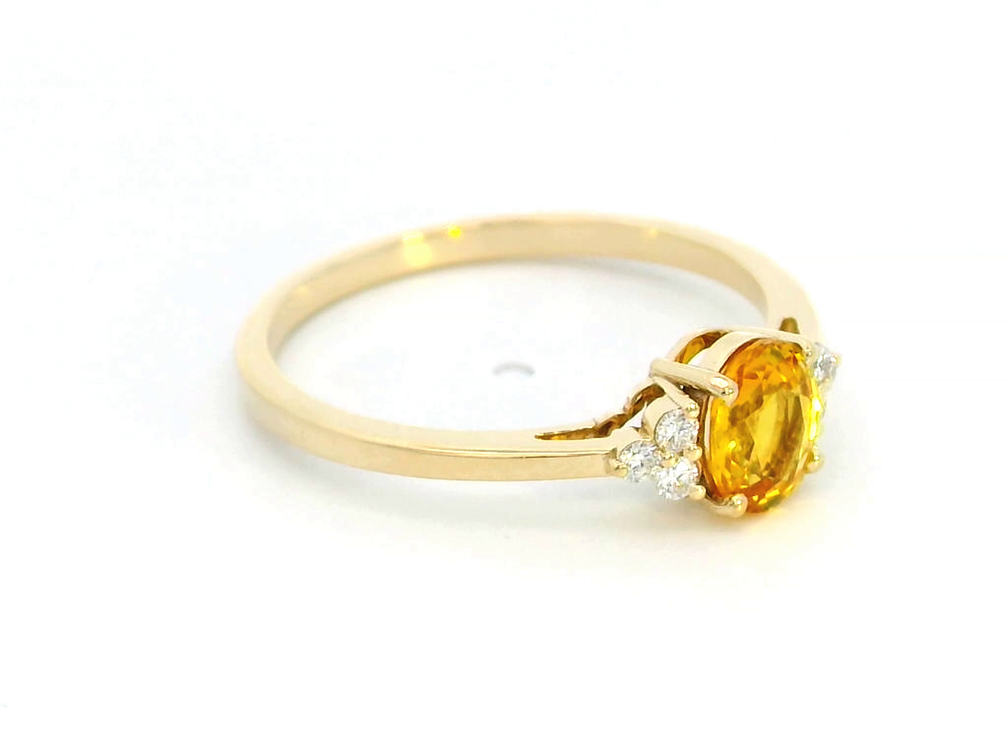 18K yellow gold ring with a 0.80-carat oval yellow sapphire and 0.09-carat diamond accents in a three-stone setting, elegant and timeless design.