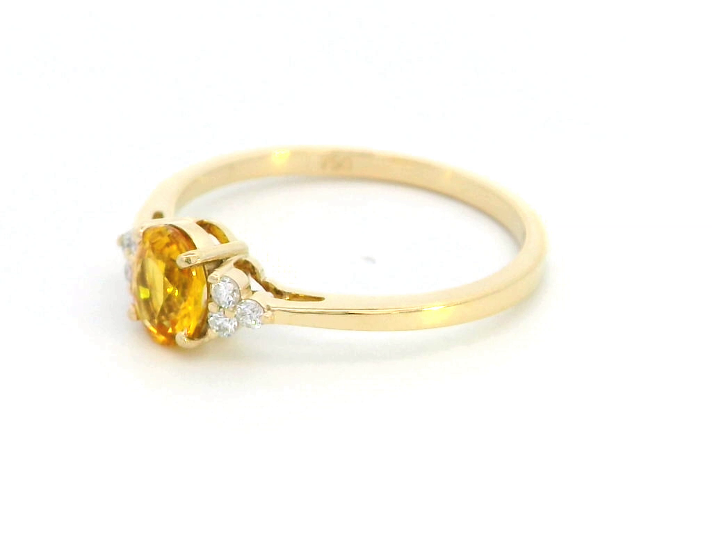 18K yellow gold ring with a 0.80-carat oval yellow sapphire and 0.09-carat diamond accents in a three-stone setting, elegant and timeless design.