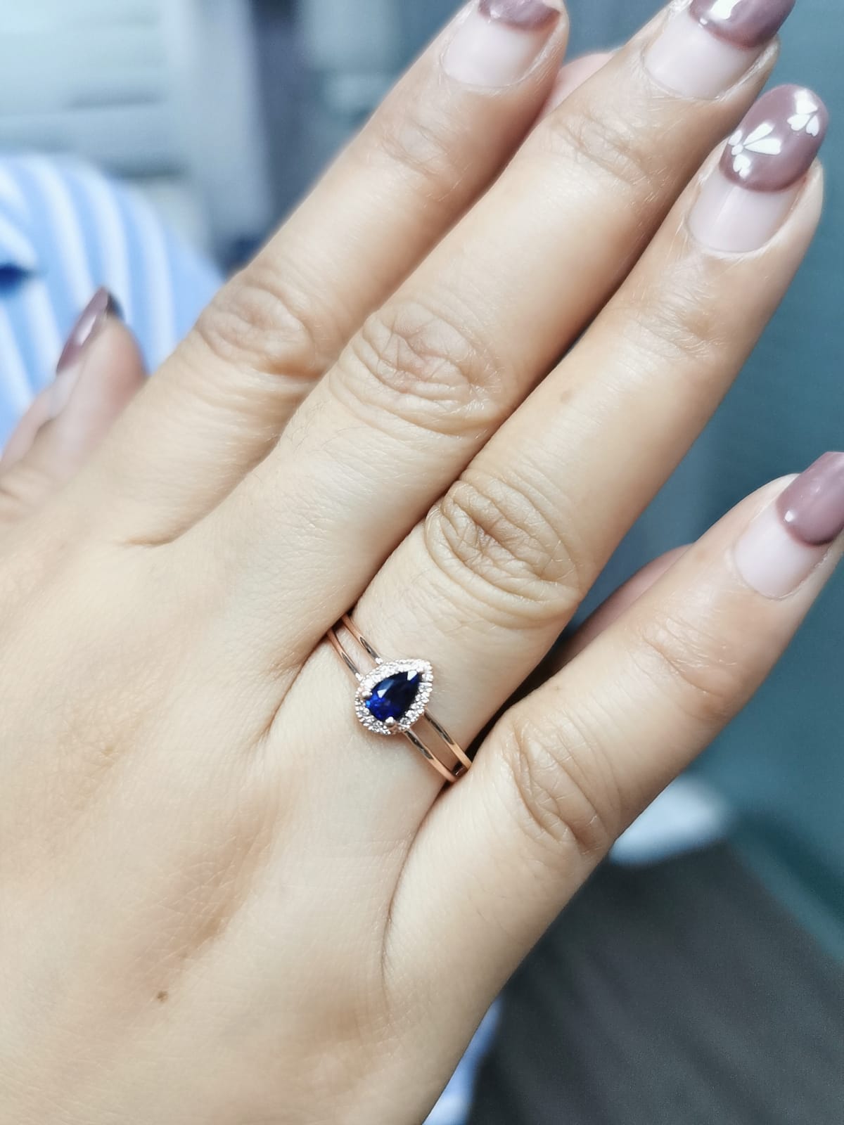 Elegant pear-shaped sapphire and diamond halo ring in 18K gold, featuring a 0.51-carat sapphire and 0.05-carat diamonds in a modern double-band design.