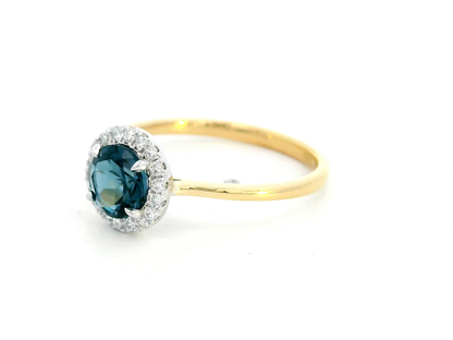 18K yellow gold ring with a 0.92-carat round-cut London blue topaz framed by a 0.15-carat diamond halo – elegant fine jewelry.