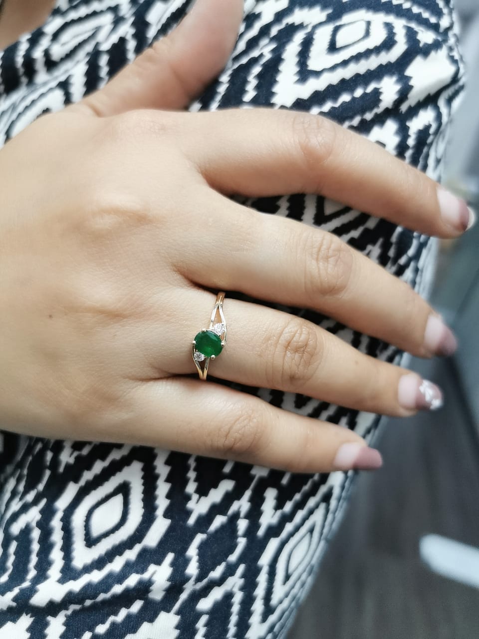 18K yellow gold ring featuring a 0.75-carat round-cut emerald with 0.10-carat diamond accents on a split-shank band – fine jewelry.