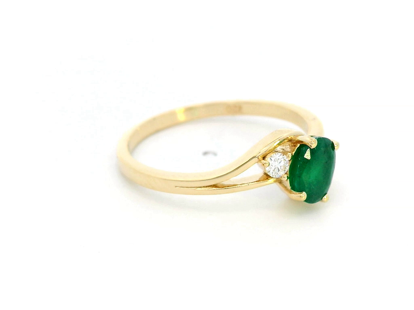 18K yellow gold ring featuring a 0.75-carat round-cut emerald with 0.10-carat diamond accents on a split-shank band – fine jewelry.