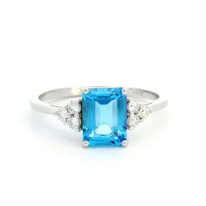 Elegant Swiss Blue Topaz and diamond ring in 18K gold, featuring a 1.66-carat emerald-cut Swiss Blue Topaz flanked by 0.17-carat diamonds in a classic three-stone design.