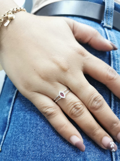 Elegant 18K gold ring featuring a marquise-cut ruby (0.14 carats) encircled by a halo of round-cut diamonds (0.05 carats) with a sleek split band design.