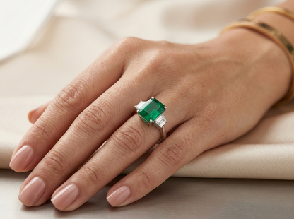 18K White Gold Emerald Three Stone Ring featuring a 3.47 carat emerald-cut natural emerald with 0.64 carat trapezoid diamonds.