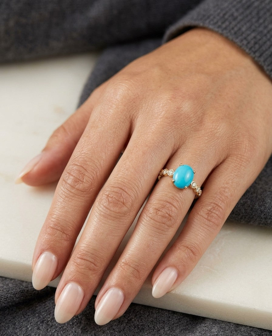 Turquoise and diamond ring in 18K yellow gold featuring an oval turquoise cabochon with round diamond accents along the band