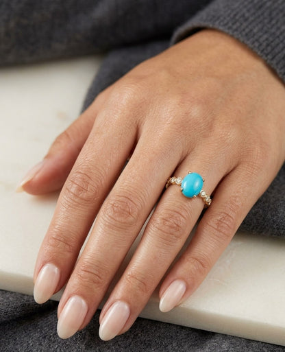 Turquoise and diamond ring in 18K yellow gold featuring an oval turquoise cabochon with round diamond accents along the band