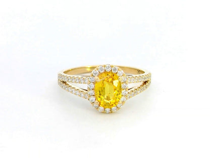 Yellow sapphire and diamond halo ring in 18K yellow gold featuring a 1.21-carat oval yellow sapphire, surrounded by a diamond halo and a split band adorned with diamonds, totaling 0.35 carats, with a smooth polished gold finish