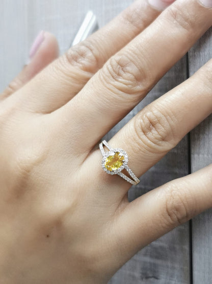 Yellow sapphire and diamond halo ring in 18K yellow gold featuring a 1.21-carat oval yellow sapphire, surrounded by a diamond halo and a split band adorned with diamonds, totaling 0.35 carats, with a smooth polished gold finish