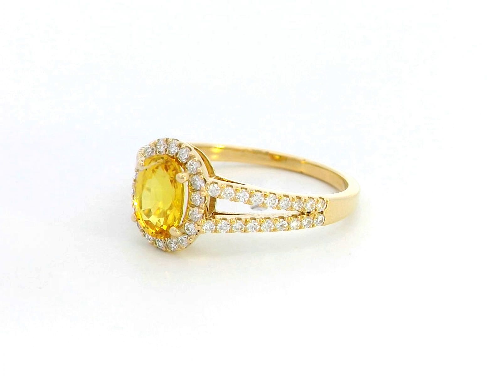 Yellow sapphire and diamond halo ring in 18K yellow gold featuring a 1.21-carat oval yellow sapphire, surrounded by a diamond halo and a split band adorned with diamonds, totaling 0.35 carats, with a smooth polished gold finish