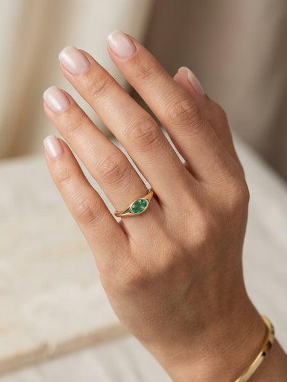 Oval emerald signet ring in 18K yellow gold with a smooth bezel setting and tapered gold shoulders
