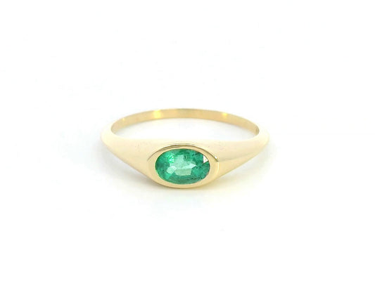 18K yellow gold ring featuring a 0.44-carat oval-shaped emerald in a bezel setting.