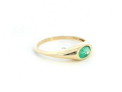 18K yellow gold ring featuring a 0.44-carat oval-shaped emerald in a bezel setting.