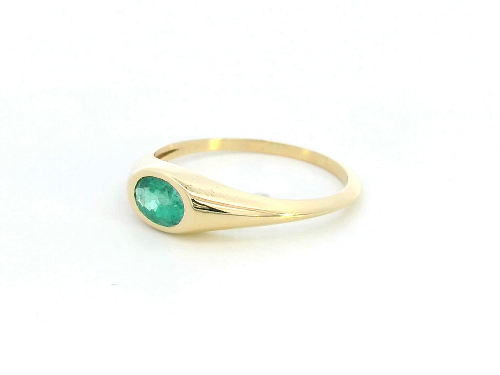 18K yellow gold ring featuring a 0.44-carat oval-shaped emerald in a bezel setting.