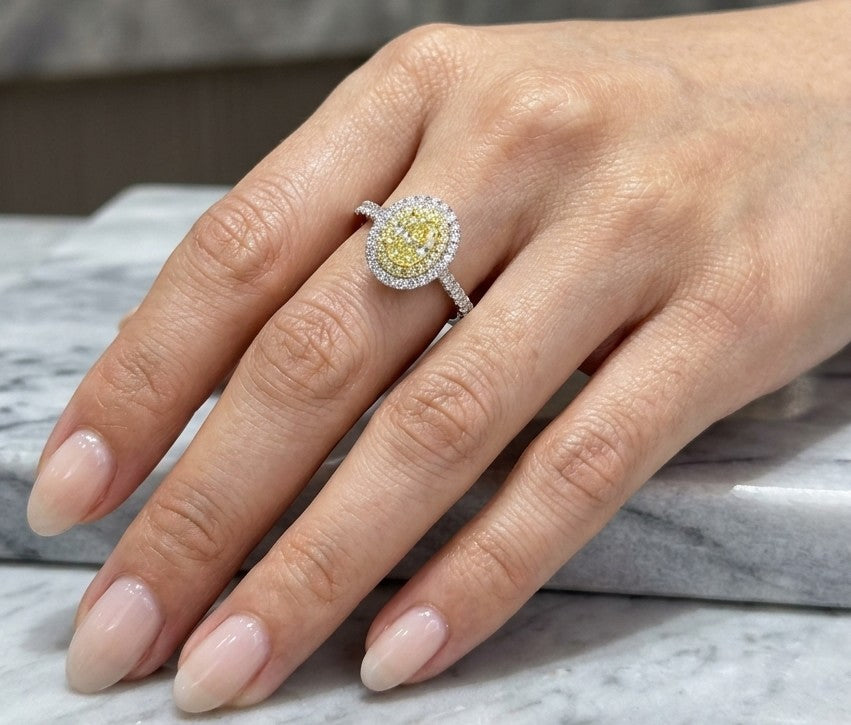 Oval fancy yellow diamond engagement ring in 18K white gold with a yellow diamond inner halo, white diamond outer halo and diamond-set band.