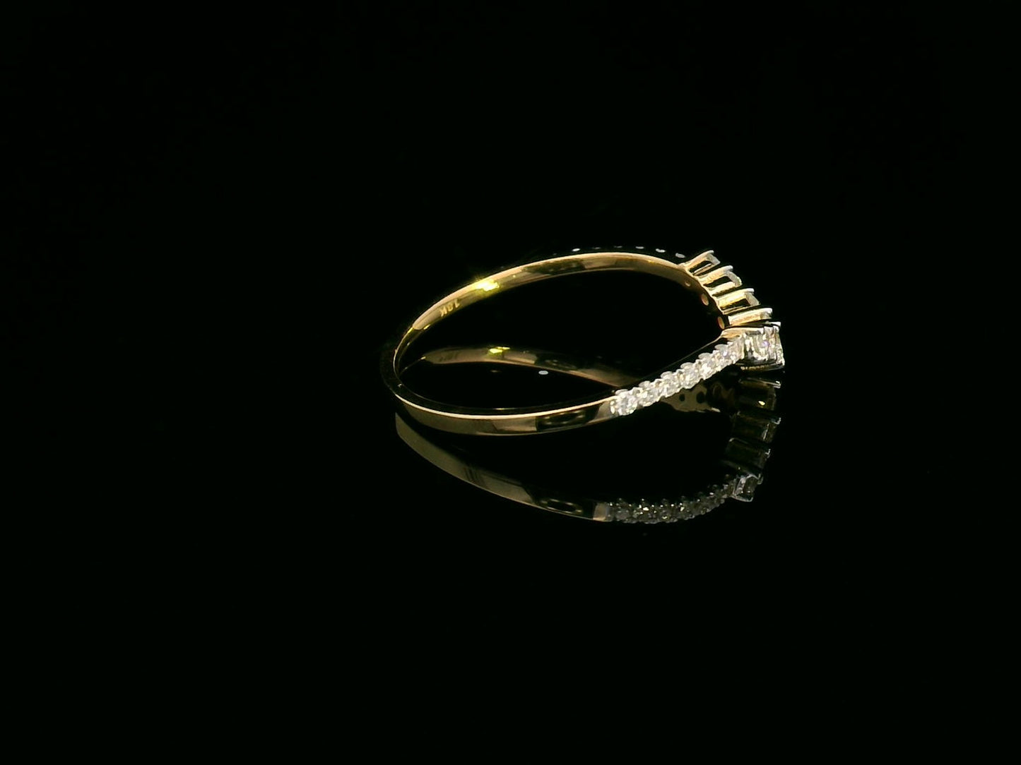 Curved diamond wedding band in 18K yellow gold with graduated round diamonds, designed for stacking or pairing with an engagement ring