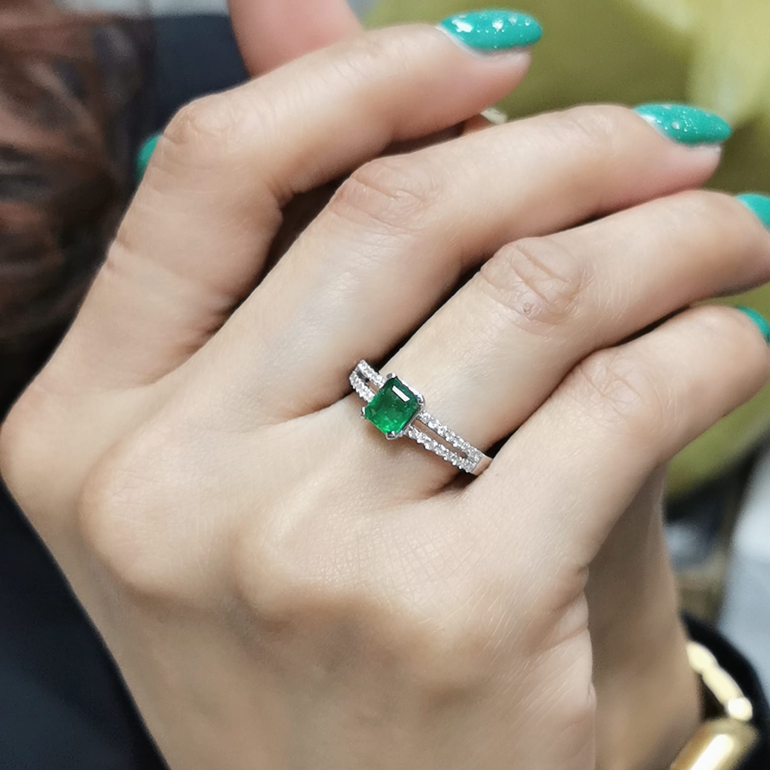 18K white gold emerald ring featuring a 0.78-carat emerald-cut green emerald with 0.25-carat diamond accents on a split band.