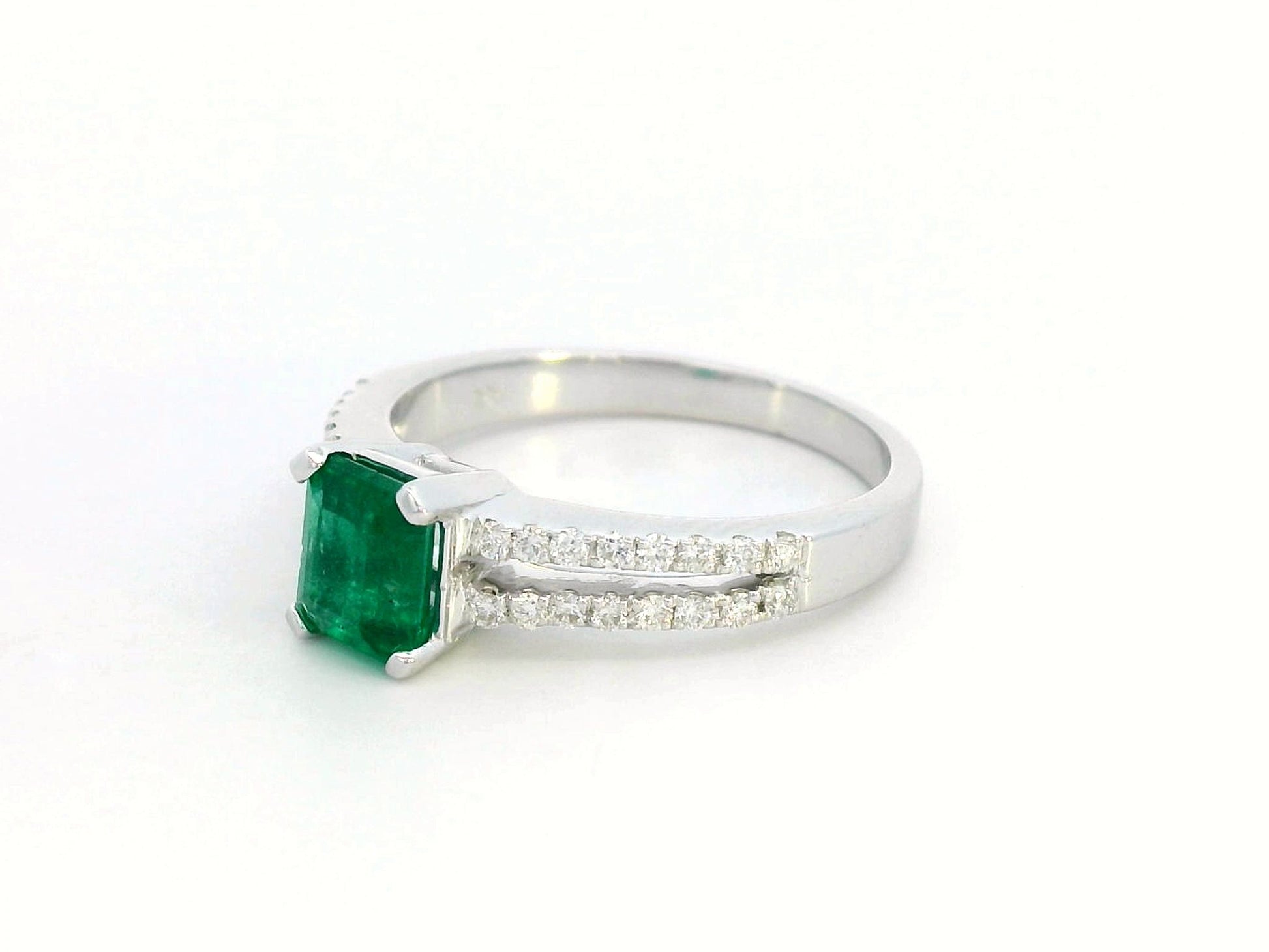 18K white gold emerald ring featuring a 0.78-carat emerald-cut green emerald with 0.25-carat diamond accents on a split band.