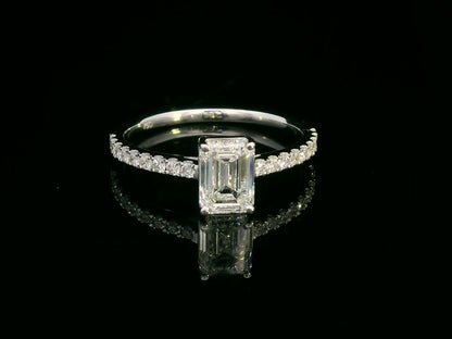 A 1.20-carat emerald-cut diamond ring set in 18K gold, featuring a diamond-studded band with 0.24 carats of round diamonds. Elegant engagement or statement jewelry.