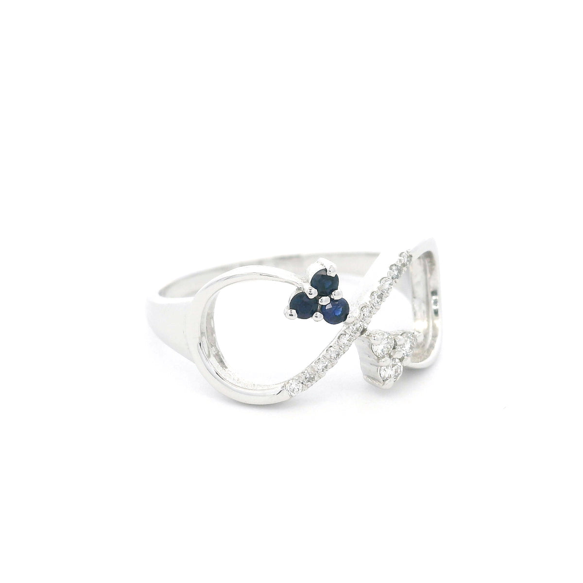 Blue sapphire and diamond infinity ring in 18K white gold with three round blue sapphires and diamond detailing.