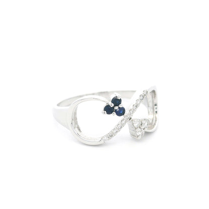 Blue sapphire and diamond infinity ring in 18K white gold with three round blue sapphires and diamond detailing.