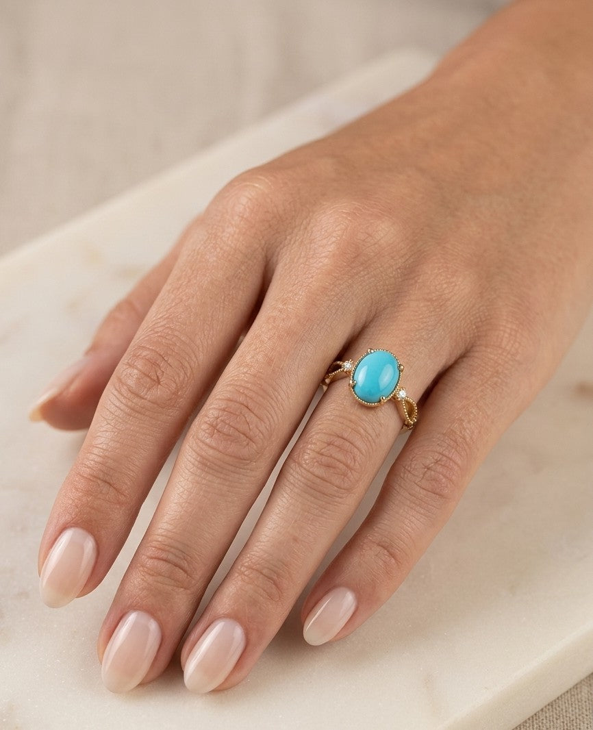 Oval turquoise and diamond ring in 18K yellow gold with open decorative shoulders and round diamond accents.