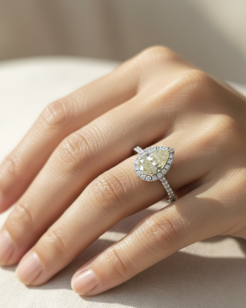 18K white gold ring featuring a 2.15 carat fancy yellow pear-shaped diamond with diamond halo and pavé band, IGI certified – Emirates Diamonds
