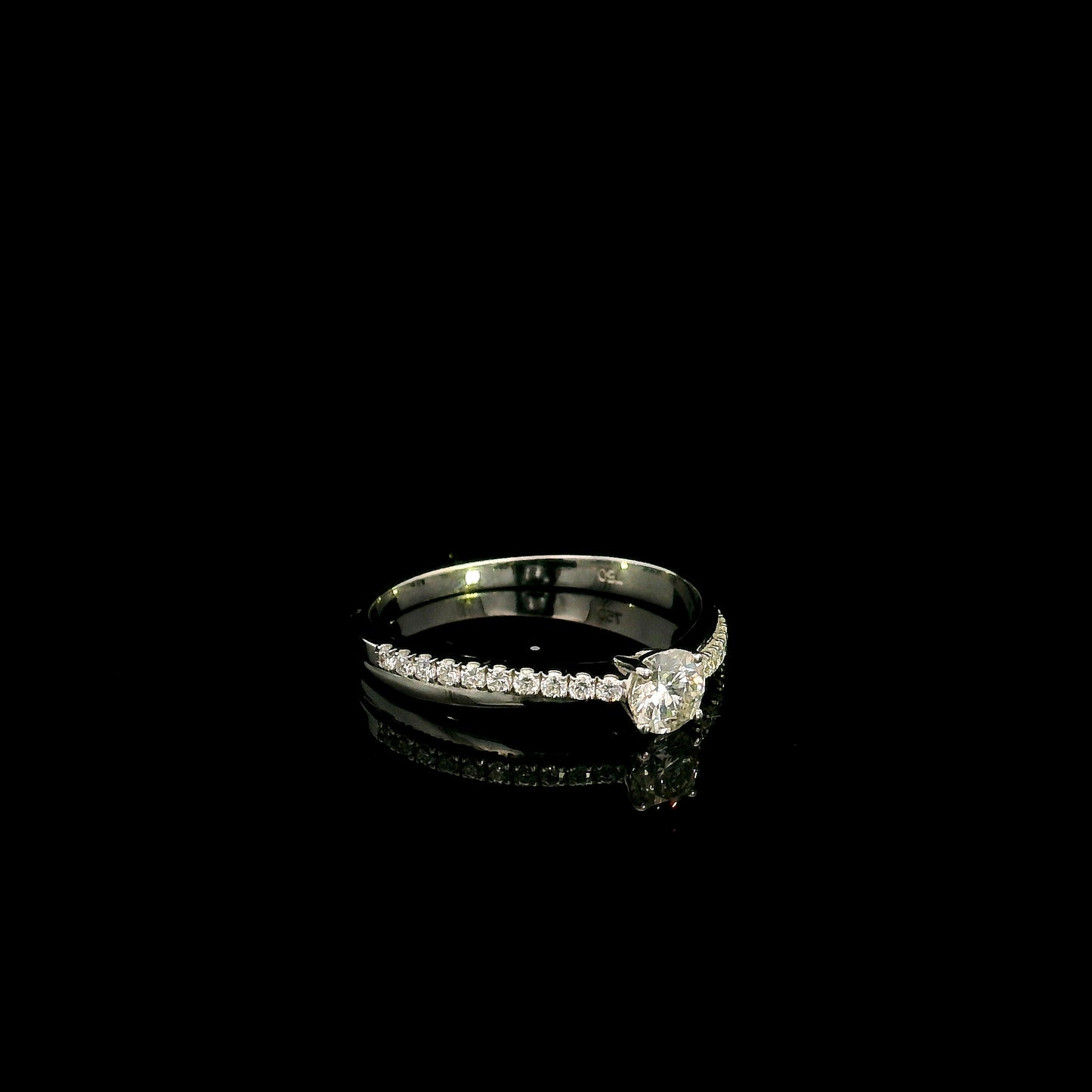 18K white gold minimalist engagement ring featuring a round brilliant diamond with an asymmetrical crossover band and pavé diamonds.