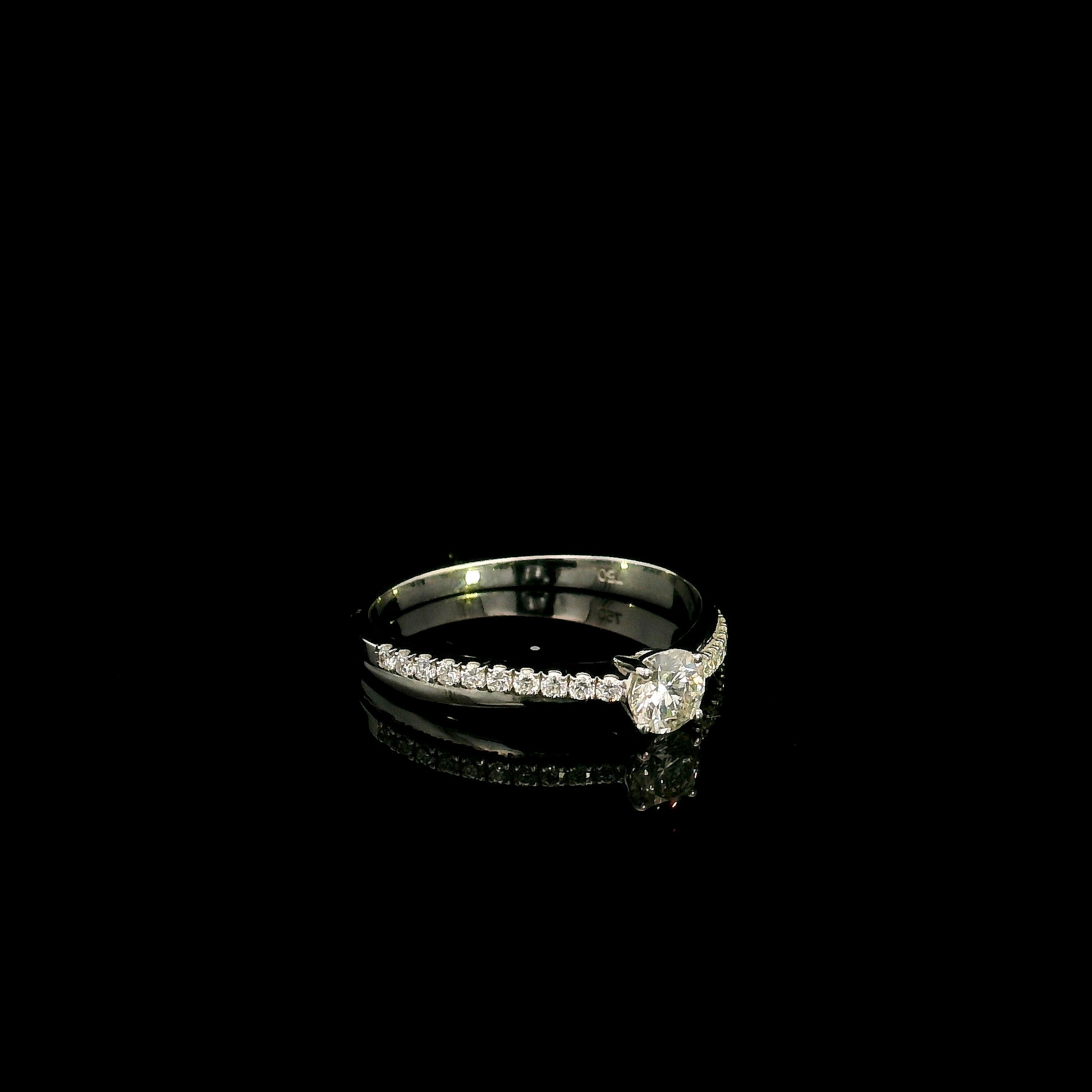18K white gold minimalist engagement ring featuring a round brilliant diamond with an asymmetrical crossover band and pavé diamonds.