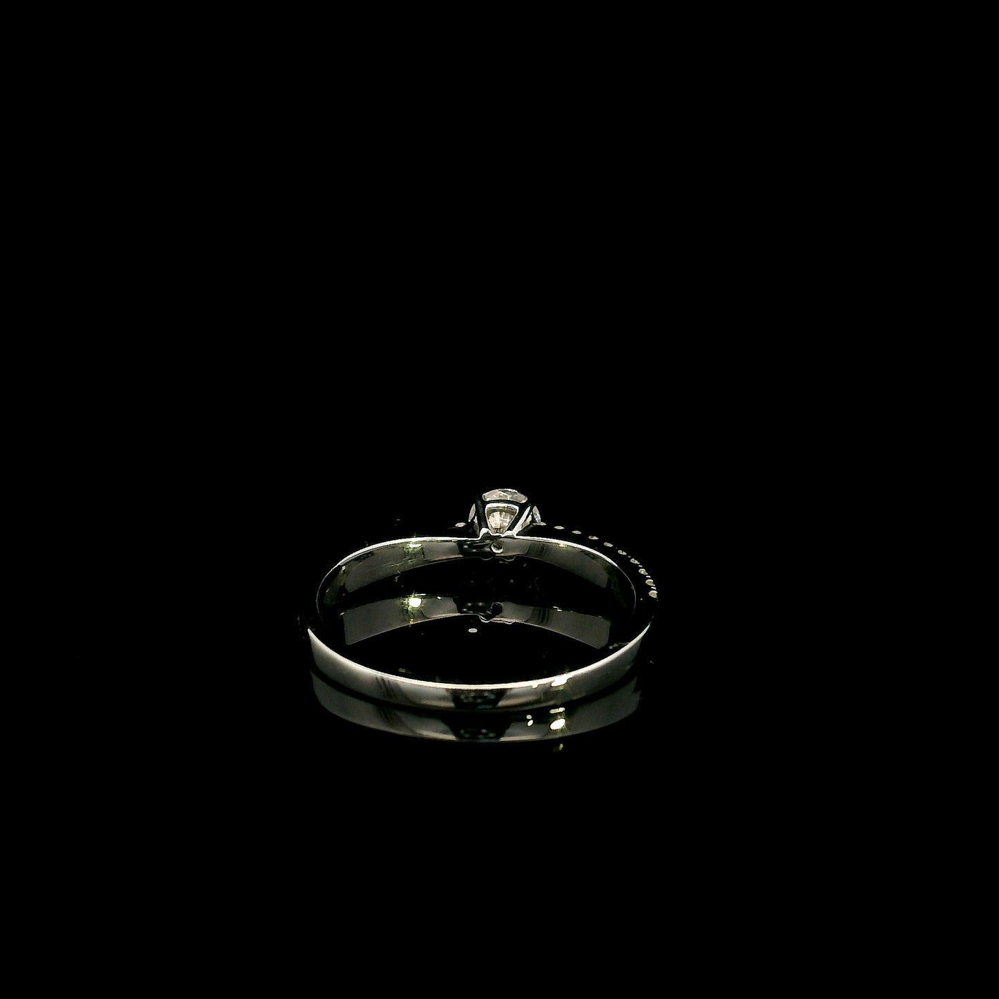 18K white gold minimalist engagement ring featuring a round brilliant diamond with an asymmetrical crossover band and pavé diamonds.