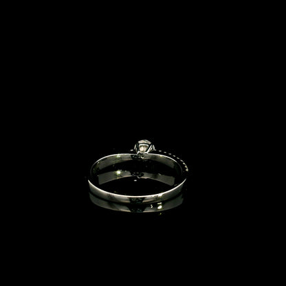18K white gold minimalist engagement ring featuring a round brilliant diamond with an asymmetrical crossover band and pavé diamonds.