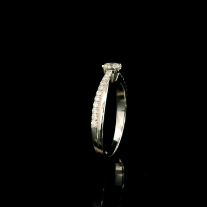 18K white gold minimalist engagement ring featuring a round brilliant diamond with an asymmetrical crossover band and pavé diamonds.