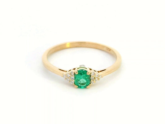 Petite 18K gold ring featuring a 0.30-carat emerald center stone, accented by 0.06-carat diamonds. Perfect for stacking or wearing alone.