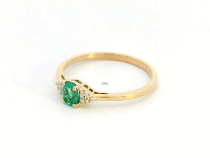 Petite 18K gold ring featuring a 0.30-carat emerald center stone, accented by 0.06-carat diamonds. Perfect for stacking or wearing alone.