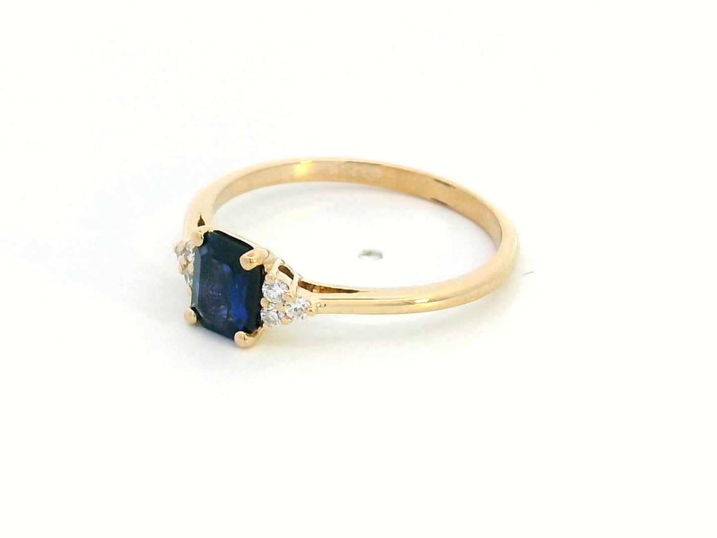 Petite 18K gold ring featuring a 0.68-carat emerald-cut blue sapphire, accented by 0.08-carat diamonds. Perfect for stacking or wearing alone.