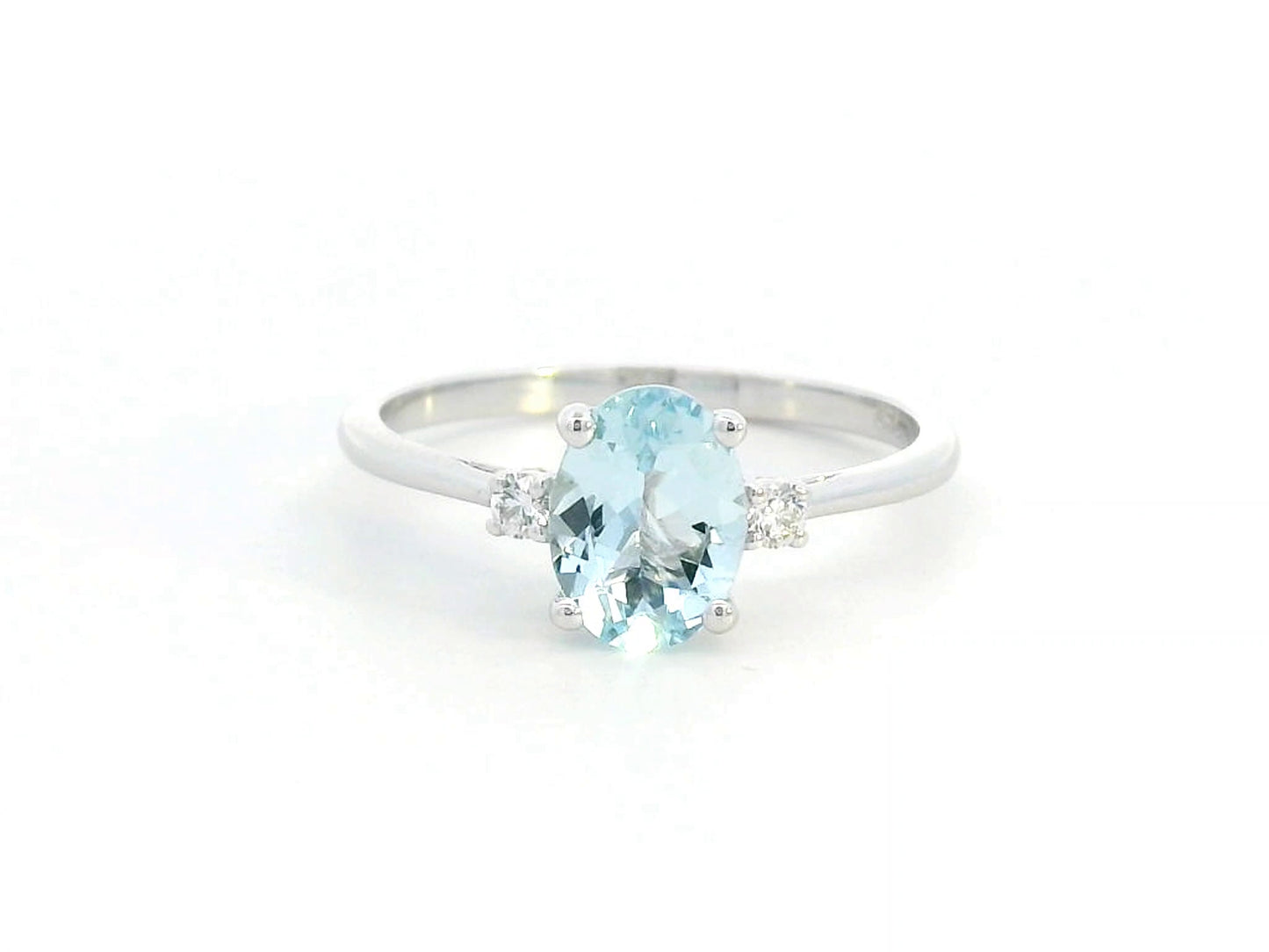 Oval Aquamarine and diamond ring in 18K gold, featuring a 0.93ct blue gemstone flanked by round-cut diamonds. 