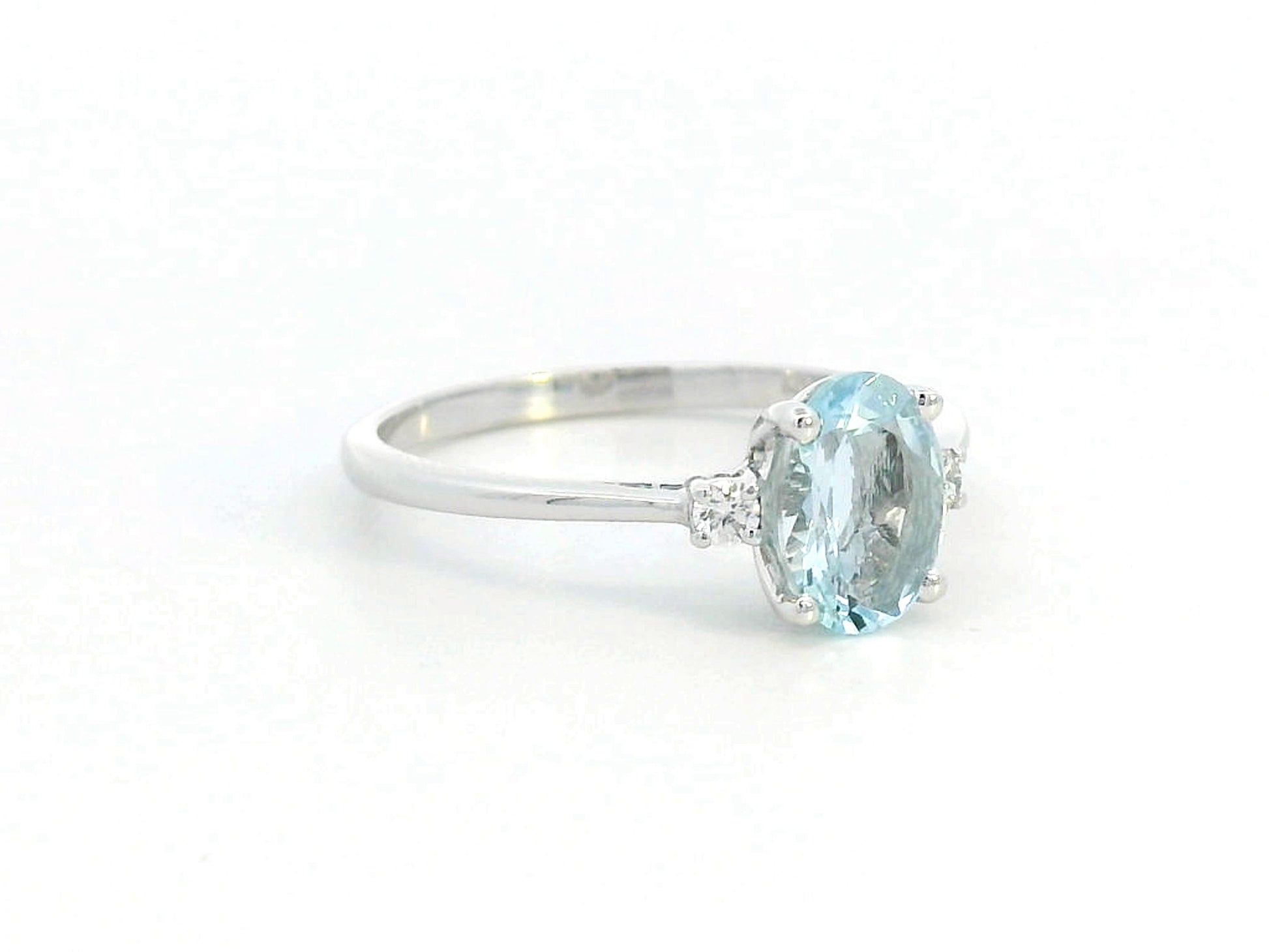 Oval Aquamarine and diamond ring in 18K gold, featuring a 0.93ct blue gemstone flanked by round-cut diamonds. 