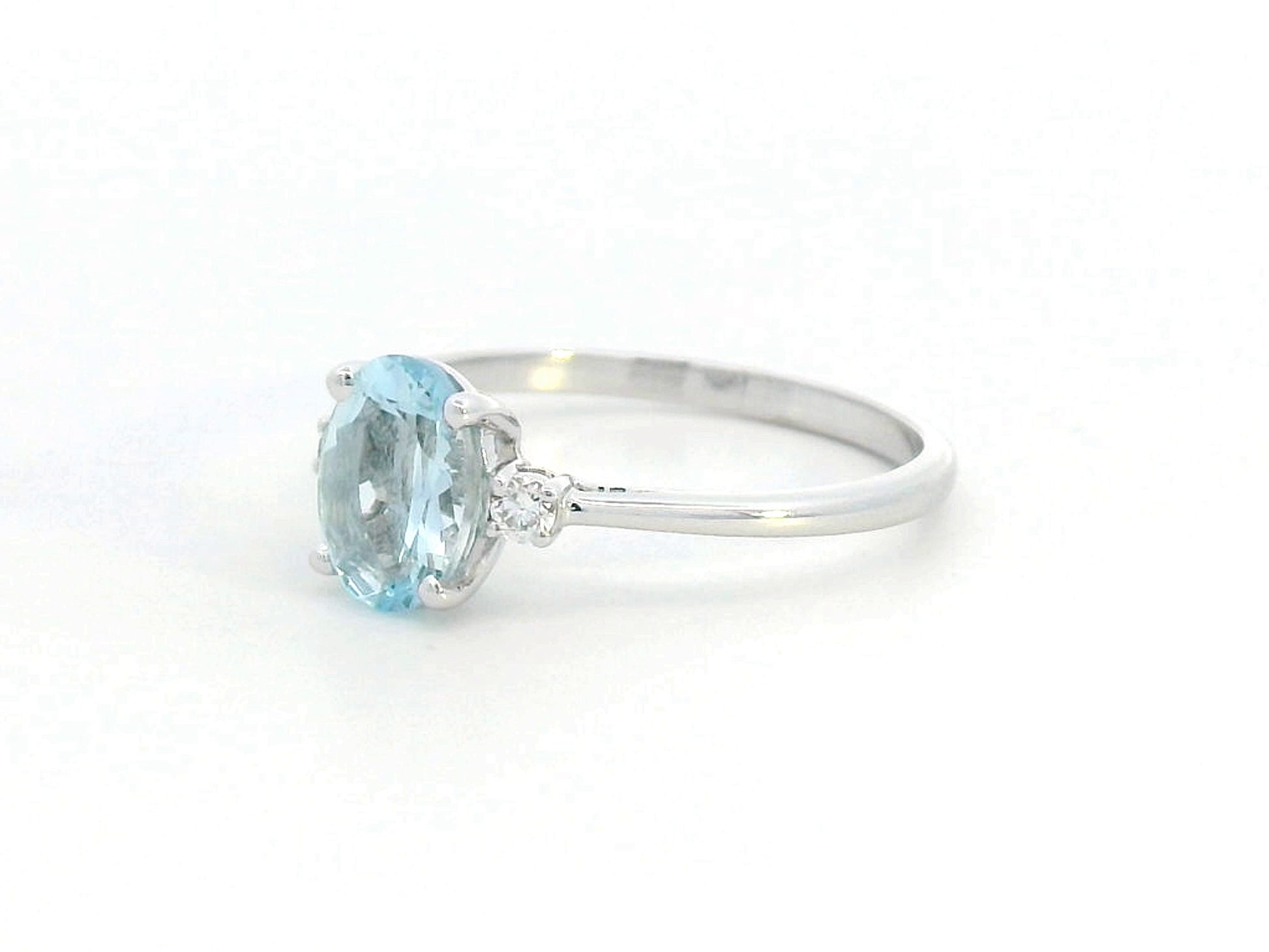 Oval Aquamarine and diamond ring in 18K gold, featuring a 0.93ct blue gemstone flanked by round-cut diamonds. 