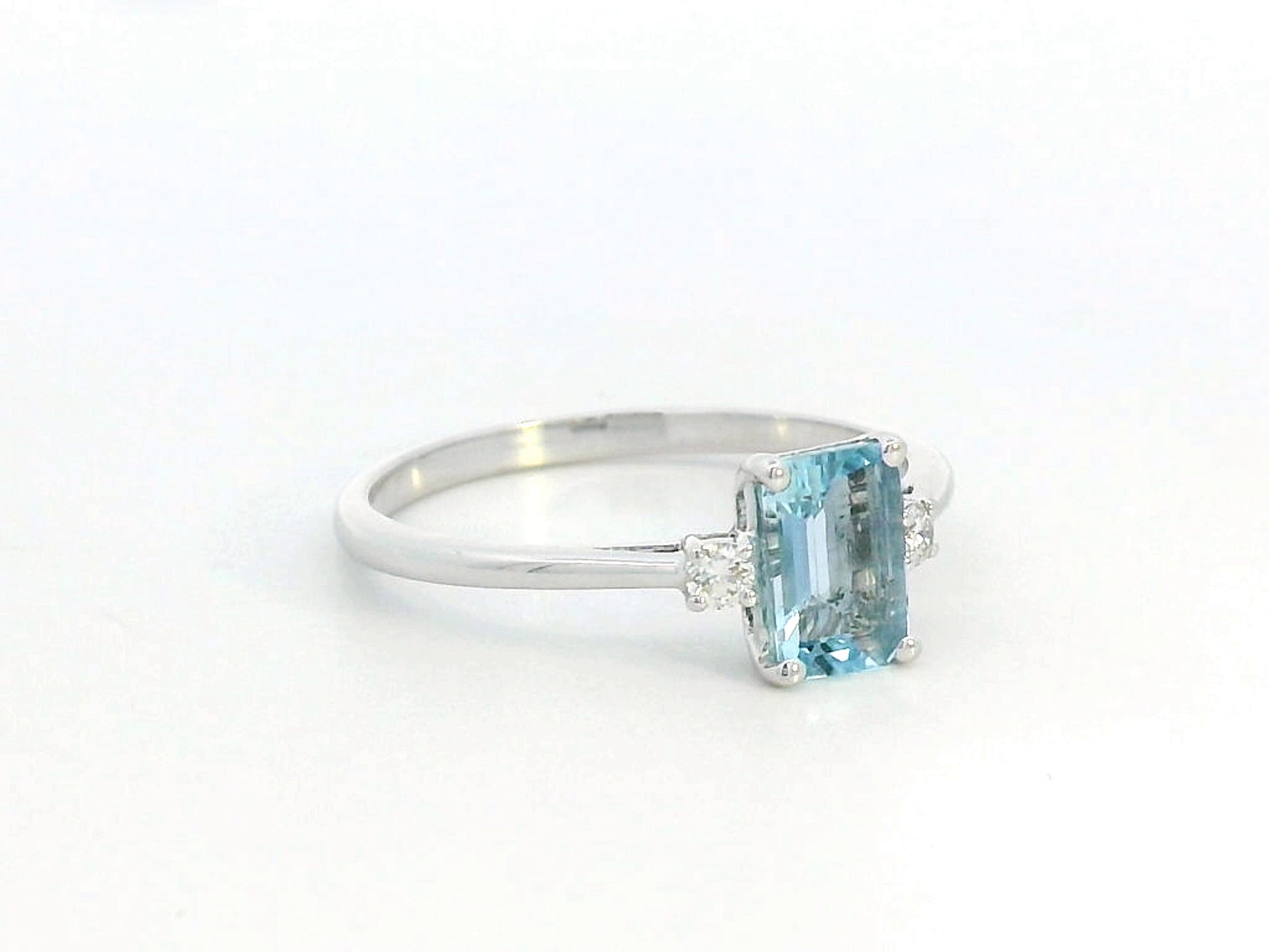 18K white gold aquamarine and diamond ring featuring a 0.65-carat emerald-cut aquamarine with 0.07-carat round diamonds in a minimalist fine jewelry design – perfect for engagements, gifts, and March birthstone jewelry.