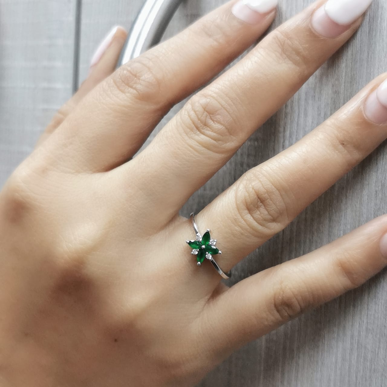 18K gold floral ring featuring 0.31 CT natural emeralds and 0.05 CT diamonds, designed in a delicate flower shape.