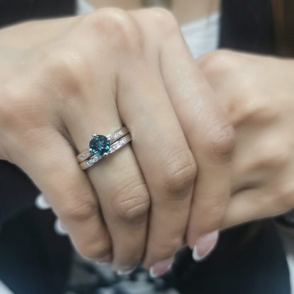 Elegant 18K White Gold London Blue Topaz and Diamond Bridal Ring Set featuring a 0.96-carat round-cut topaz and 0.18-carat diamonds on an engagement ring and matching wedding band