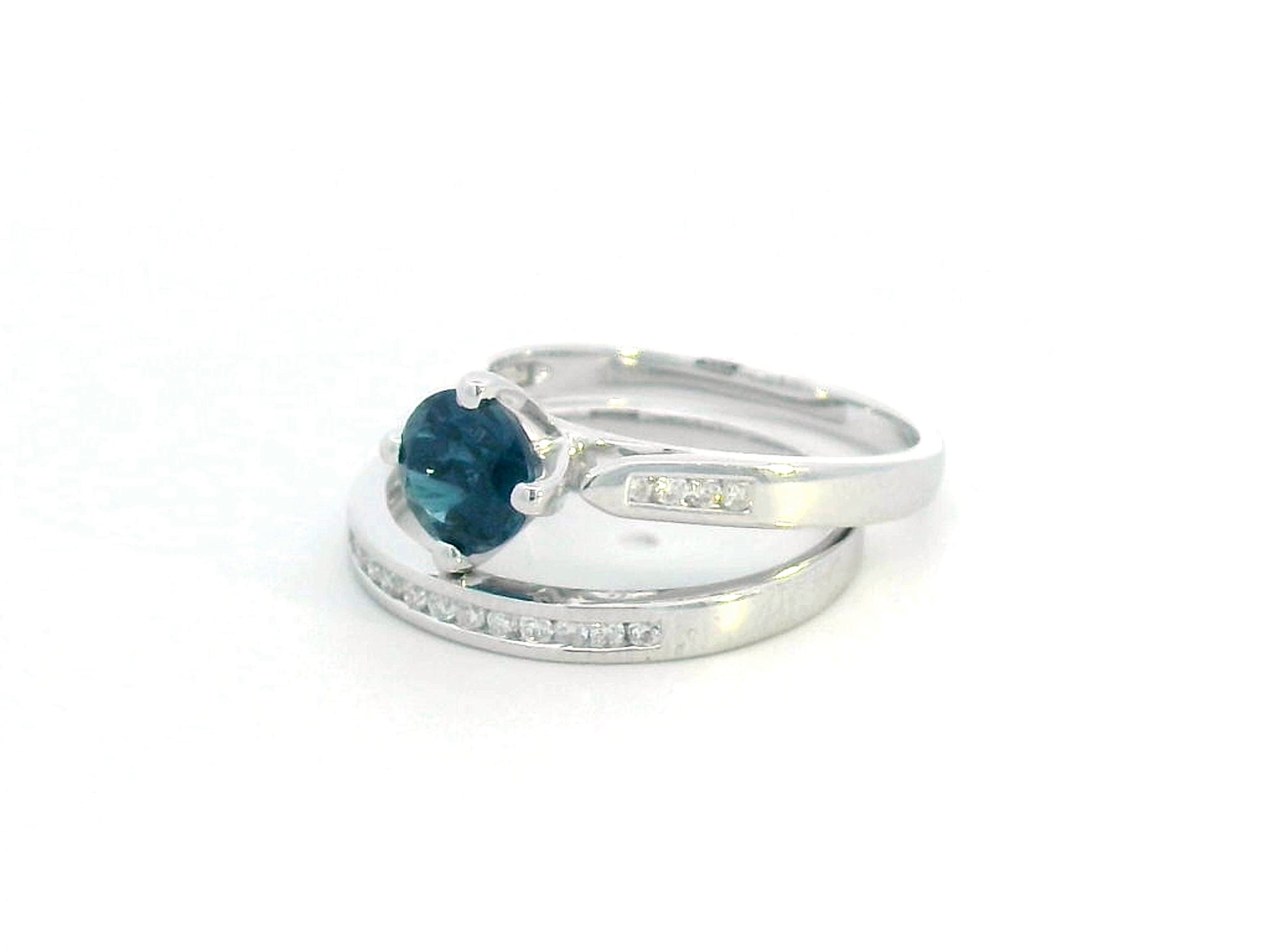 Elegant 18K White Gold London Blue Topaz and Diamond Bridal Ring Set featuring a 0.96-carat round-cut topaz and 0.18-carat diamonds on an engagement ring and matching wedding band