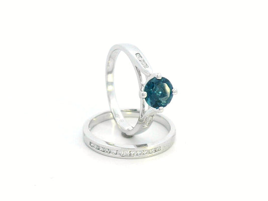 Elegant 18K White Gold London Blue Topaz and Diamond Bridal Ring Set featuring a 0.96-carat round-cut topaz and 0.18-carat diamonds on an engagement ring and matching wedding band