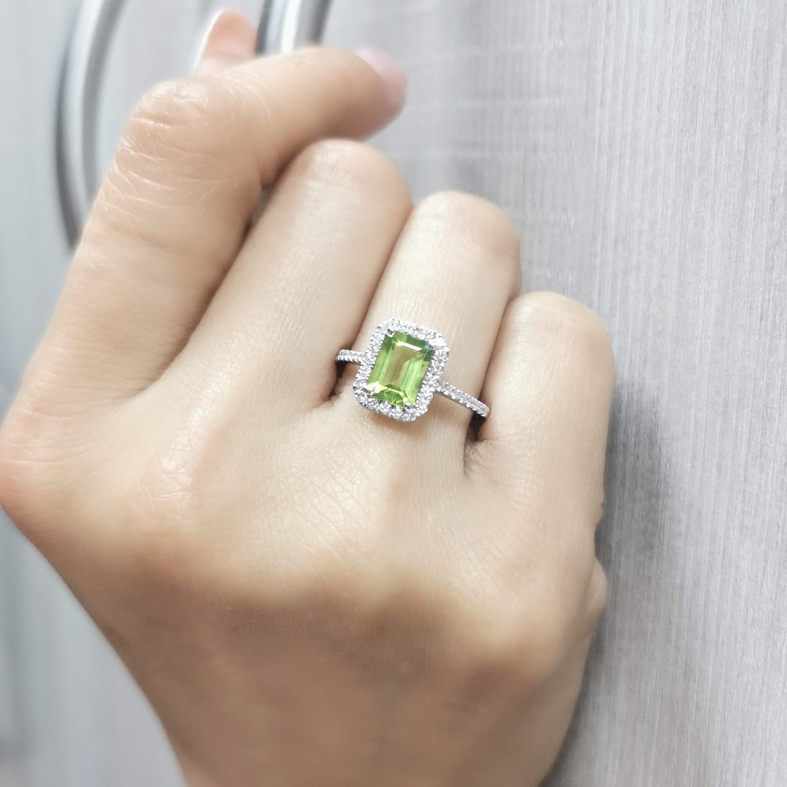 18K white gold emerald-cut Peridot ring with 0.35ct diamond halo, featuring 1.58ct Peridot centerpiece.